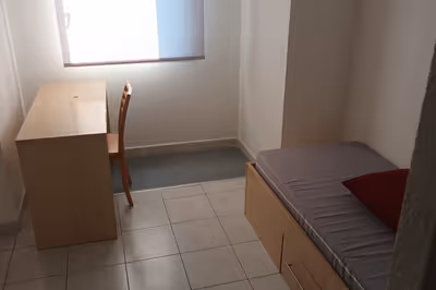 Espace principal d'un studio T1 meublé avec lit, bureau et rangements